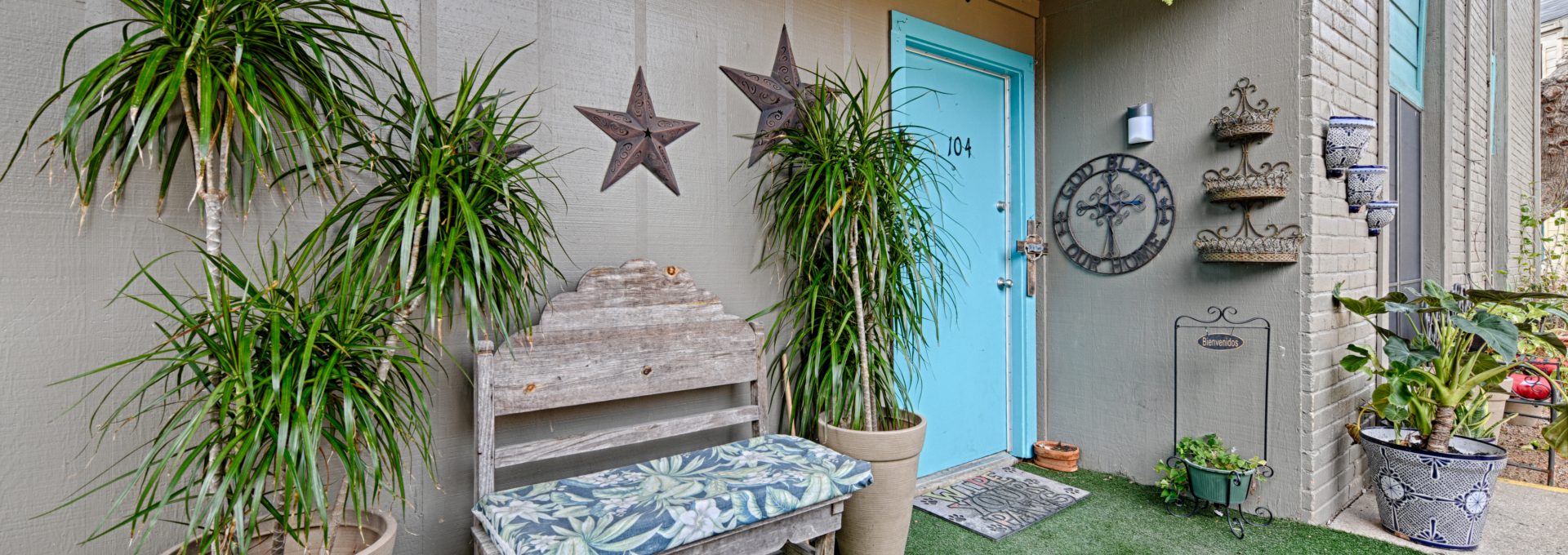 a small patio with plants and a bench at The Gateway Apartments