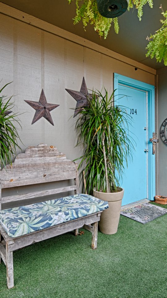 a small patio with plants and a bench at The Gateway Apartments