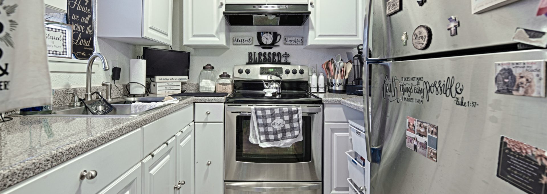 a kitchen with white cabinets and stainless steel appliances at The Gateway Apartments